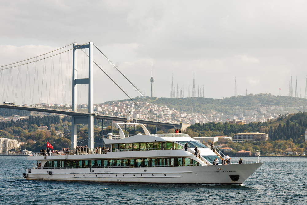 A Bosphorus cruise boat sailing between Europe and Asia under the bridge in Istanbul